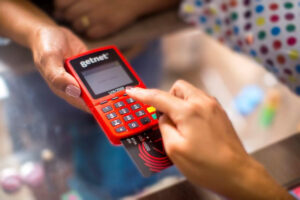 Foto de mão digitando senha em máquina de cartão da Getnet