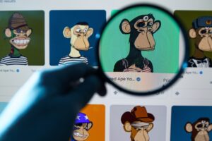 Mão segurando uma lupa e aumentando imagens de NFTs