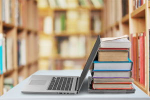Notebook ao lado de pilha de livros
