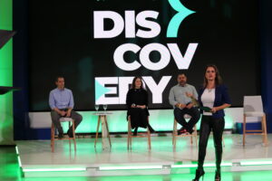 Palco do evento Discovery, com a mediadora e os convidados: Gabriel Navarro e Breno Perrucho.
