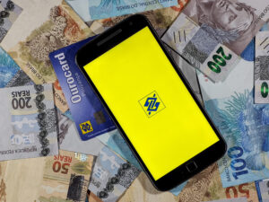 Celular com logo do Banco do Brasil e notas de dinheiro