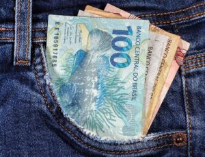 Foto de cédulas de real saindo de bolso de calça jeans