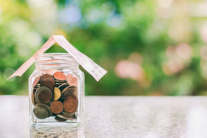 Pote transparente com moedas dentro e uma cédula provada em cima