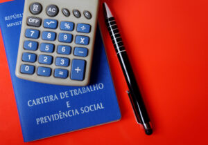 Carteira de trabalho com uma calculadora em cima e uma caneta ao lado