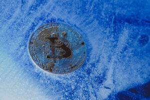Um moeda com o símbolo do Bitcoin enterrada em um bloco de gelo