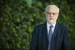 Homem branco vestindo terno escuro, camisa clara e gravata escura