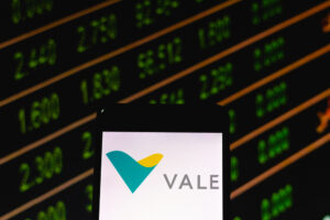 Celular com logo da Vale e gráfico de ações no fundo