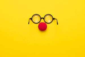 Óculo de grau e um nariz vermelho de palhaço com um fundo amarelo