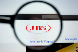 Computador aberto no site da JBS observado por uma lupa