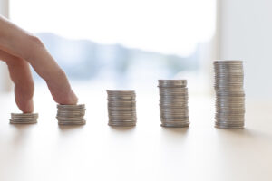 Pilhas de moeda colocadas de forma escalonada com dois dedos em cima