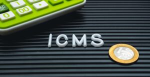 Sigla ICMS ao lado de calculadora e moeda de real.