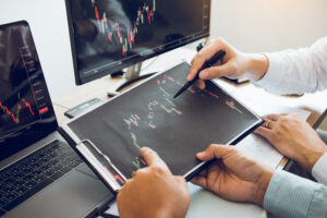 Duas pessoas segurando prancheta com impressão de gráfico de ações e apontando para pontos do gráfico