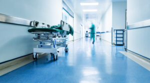 corredor de hospital com uma maca e uma pessoa ao fundo