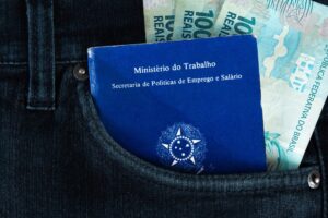 Bolso lateral de calça mostrando carteira de trabalho e notas de real