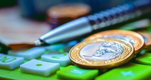 Moedas de real com caneta e calculadora