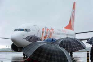 Avião da gol em dia chuvoso, com pessoas de guarda-chuva na frente