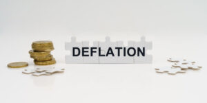 Ao centro, peças de quebra-cabeças formanda a palavra deflation; do lado esquerdo peças de quebra-cabeça em branco junto com moedas; e na direita, apenas peças de quebra-cabeça em branco.