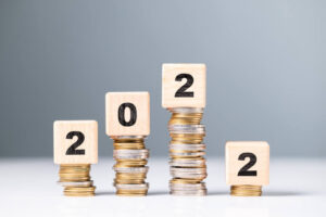 Quatro pilhas de moedas enfileiradas de diferentes tamanhos com cubos em cima de cada uma formando o ano 2022.