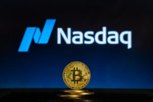 Moeda de Bitcoin em frente marca da Nasdaq