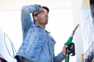 homem segura mangueira de bomba de gasolina com expressão de espanto