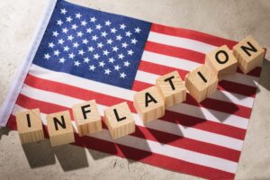 Bandeira americana com blocos formando a palavra "inflação" em inglês