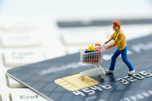 Boneco empurrando carrinho de supermercado em cima de um cartão