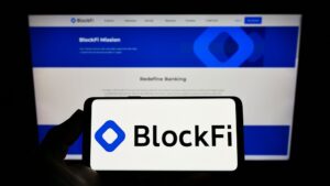 Logo da BlockFi em tela de celular com site da empresa ao fundo