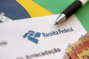 Papel com carimbo da Receita Federal em cima de bandeira do Brasil